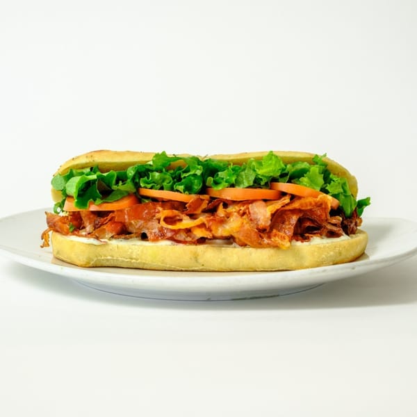 A healthy Garden of Eat'n sub sandwich with lettuce, tomatoes, and meat on a white plate.