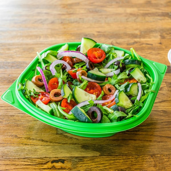 A vibrant Garden of Eat'n salad with mixed greens, tomatoes, cucumbers, red onions, and olives.
