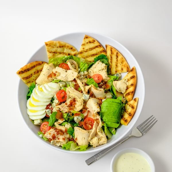 A Garden of Eat'n Cobb salad with chicken, avocado, egg, bacon, and pita bread.